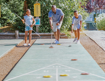 Father playing shuffleboard with his two kids
