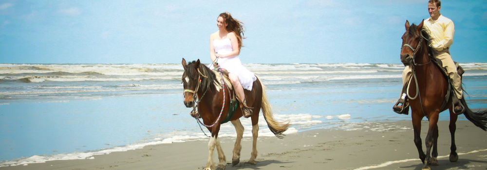 Married couple riding horses on the beach
